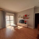 Salón luminoso con mesa de café, mueble para la televisión y estanterías